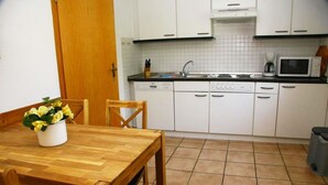 A kitchen with white cabinets, a wooden table, and a potted plant. - Schmiedeweg Whg. 2 in Westerland - comfortable apartment with terrace and sauna (Westerland)