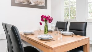 Ein Esstisch mit Tellern, Gläsern und einer Blumenvase.