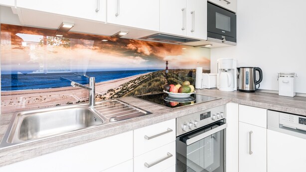 Eine moderne Küche mit Spüle aus Edelstahl, Backofen und Kaffeemaschine.