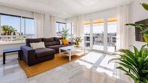 Un salon moderne avec un canapé, une table basse et de grandes fenêtres donnant sur la mer.