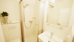 A modern bathroom with a glass-enclosed shower, a white sink, and a mirror above the sink. - Modern apartment in Westerland with balcony, parking and WiFi (Westerland)