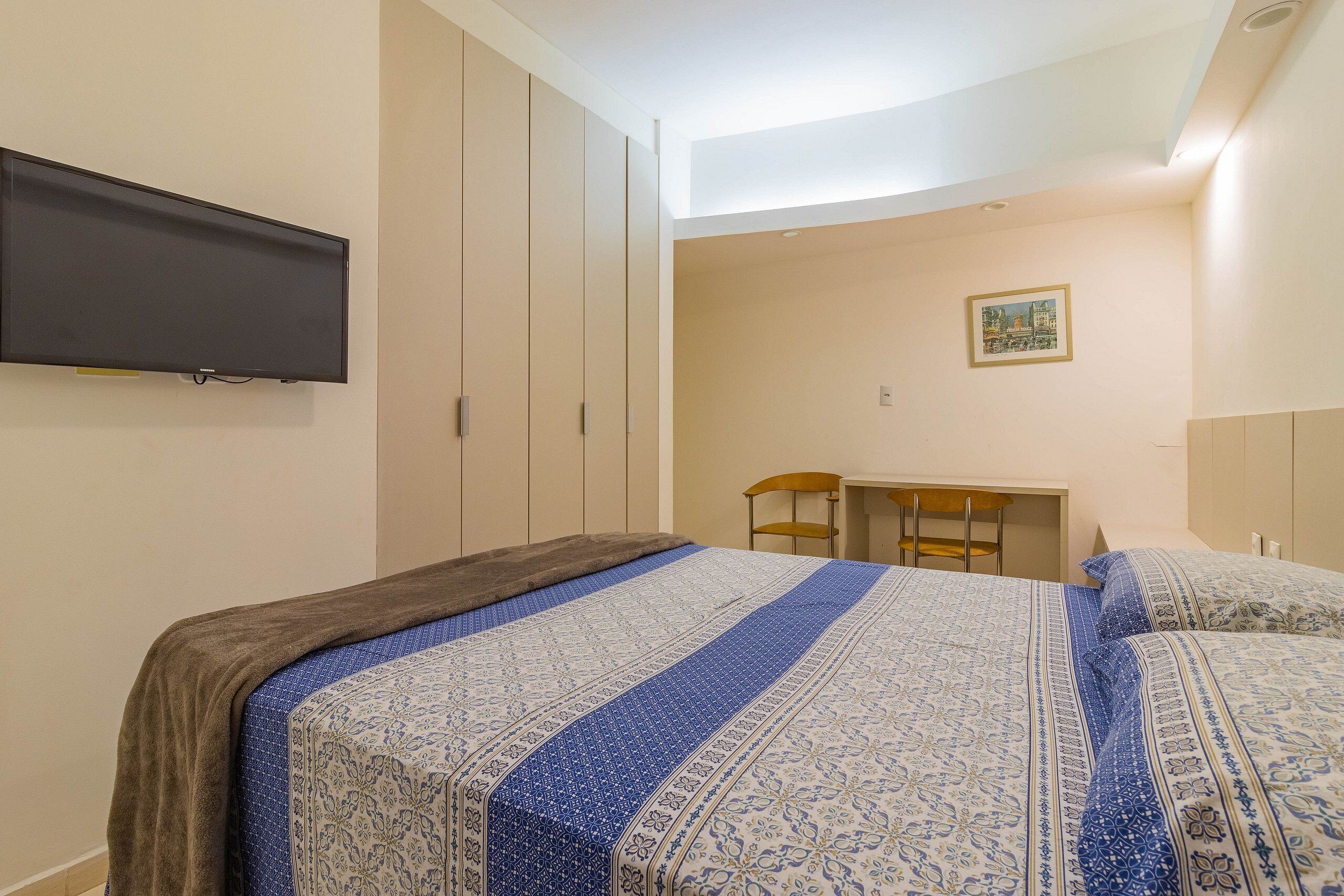 A bedroom with a bed, a desk, and a chair.