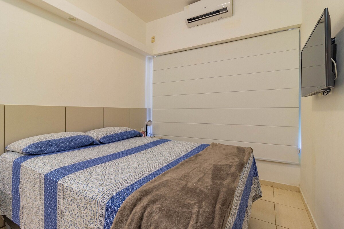 Une chambre à coucher avec un lit, un téléviseur fixé au mur et un appareil de climatisation.