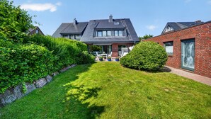 A residential house with a well-maintained lawn, a patio with outdoor furniture, and a brick exterior. - Vacation apartment Liiger Hörn 1 in Tinnum with sauna, garden and terrace (Tinnum)