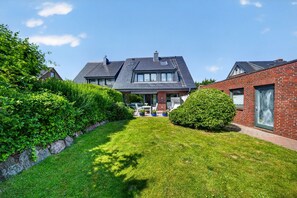A residential house with a well-maintained lawn, a patio with outdoor furniture, and a brick exterior. - Vacation apartment Liiger Hörn 1 in Tinnum with sauna, garden and terrace (Tinnum)