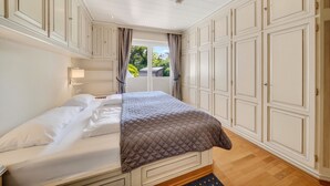 A bedroom with a bed, white walls, a window with curtains, and a view of greenery outside. - Vacation apartment Liiger Hörn 1 in Tinnum with sauna, garden and terrace (Tinnum)