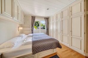 A bedroom with a bed, white walls, a window with curtains, and a view of greenery outside. - Vacation apartment Liiger Hörn 1 in Tinnum with sauna, garden and terrace (Tinnum)
