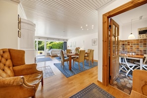 A modern living room with a leather sofa, a dining area with a wooden table and chairs, and a kitchen with a tiled backsplash. - Vacation apartment Liiger Hörn 1 in Tinnum with sauna, garden and terrace (Tinnum)