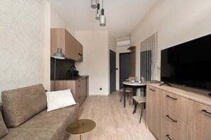 Suite estudio Deluxe, balcón | Zona de estar | Una televisión de pantalla plana