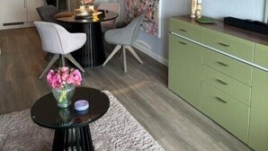 Ein modernes Wohnzimmer mit Essbereich, einem Flachbildfernseher und einer Küche im Hintergrund.