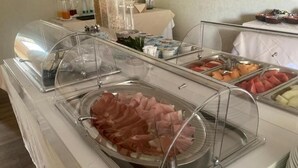A buffet with clear glass covers over food items including sliced meats, fruits, and vegetables. - hotel Villa Conte Riccardi (Rocca D'Arazzo)