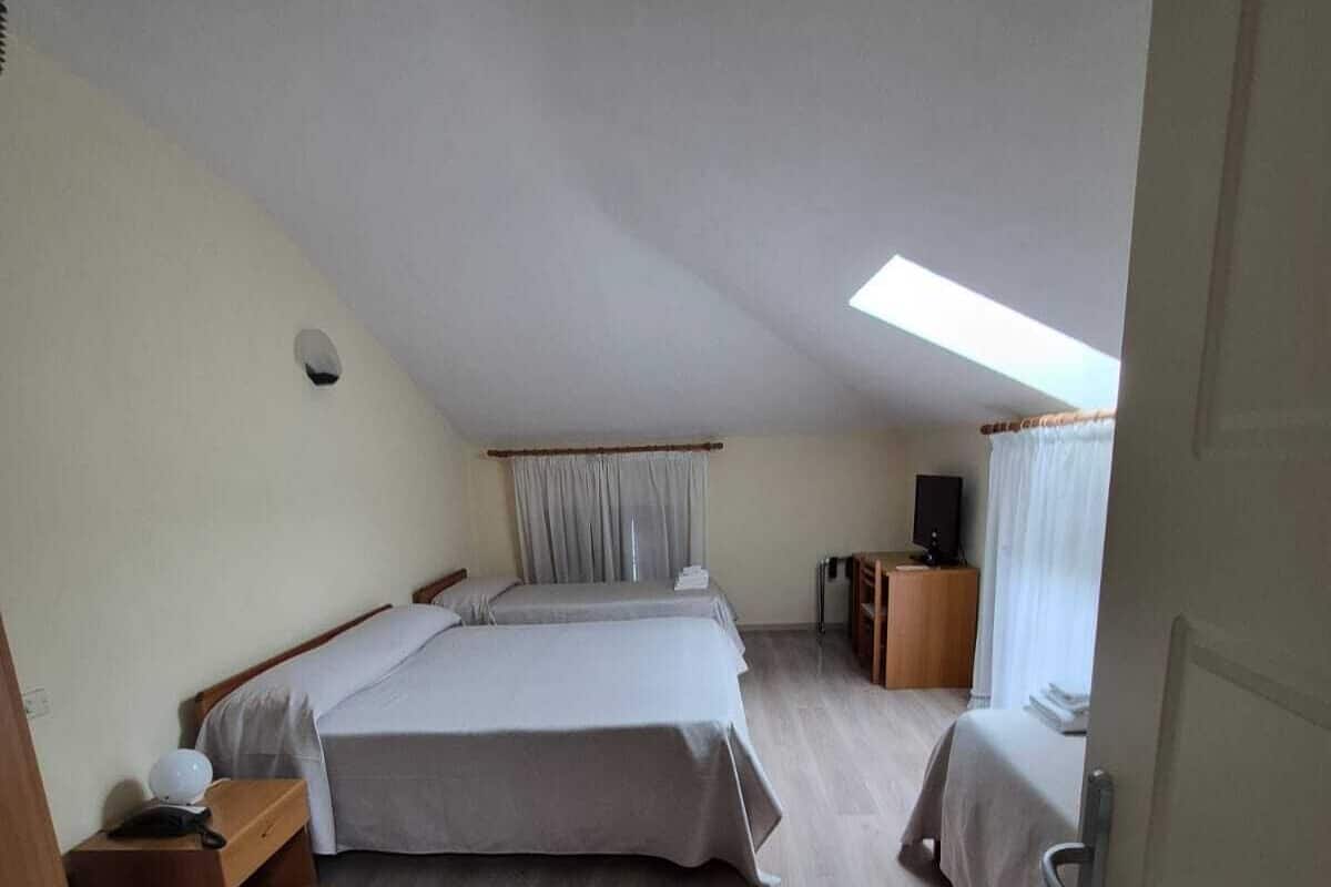 Una habitación con una cama grande, un escritorio, una silla, un televisor y un tragaluz.