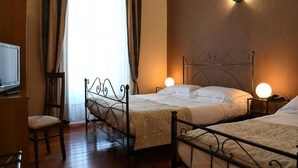A hotel room with two beds, a television, and a chair. - hotel Villa Conte Riccardi (Rocca D'Arazzo)
