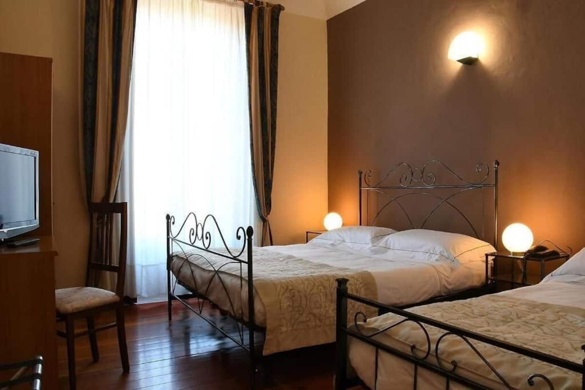 Una habitación de hotel con dos camas, televisión y una silla.