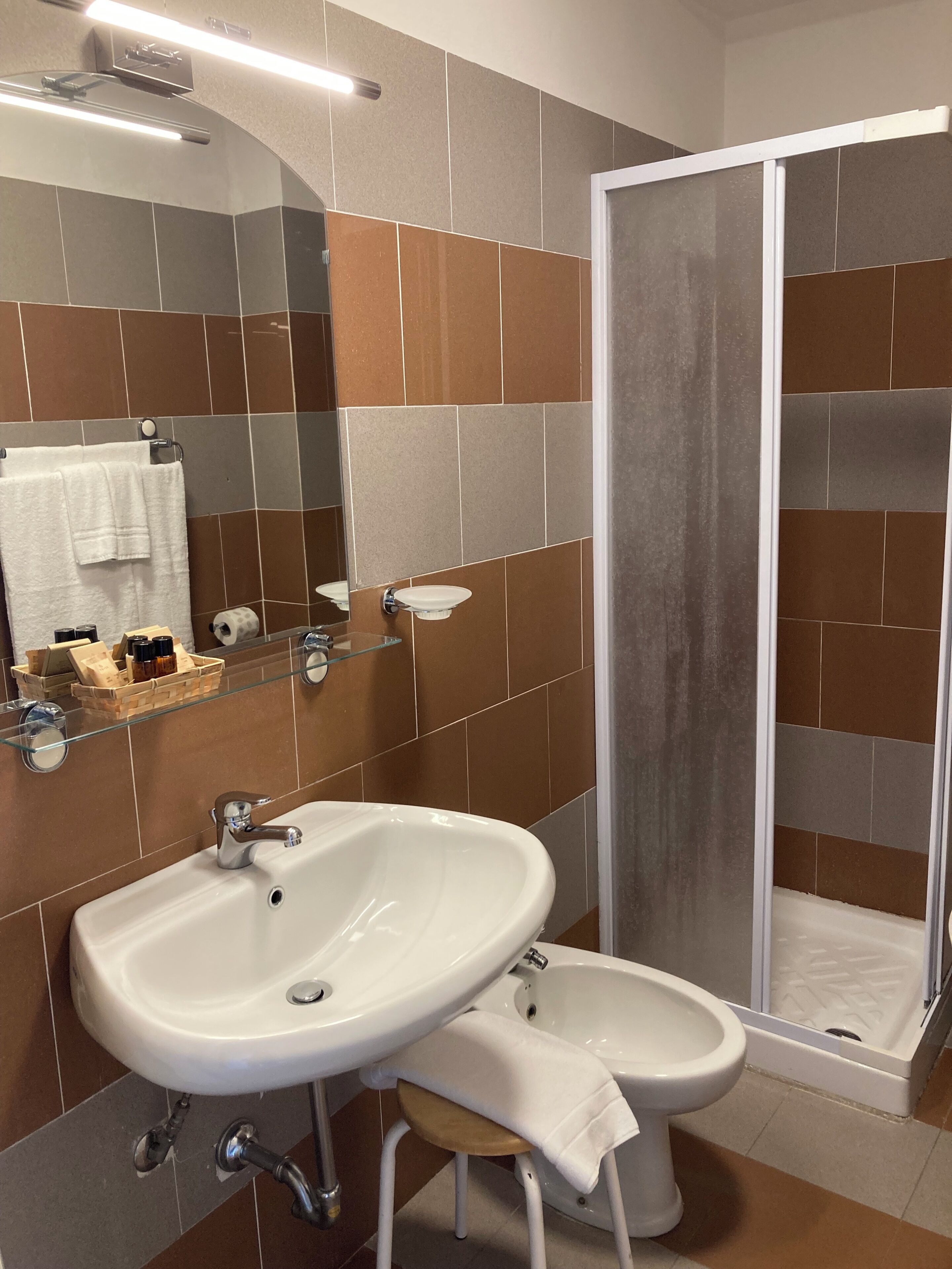 Et badeværelse med vask, spejl, brusebad og toilet.