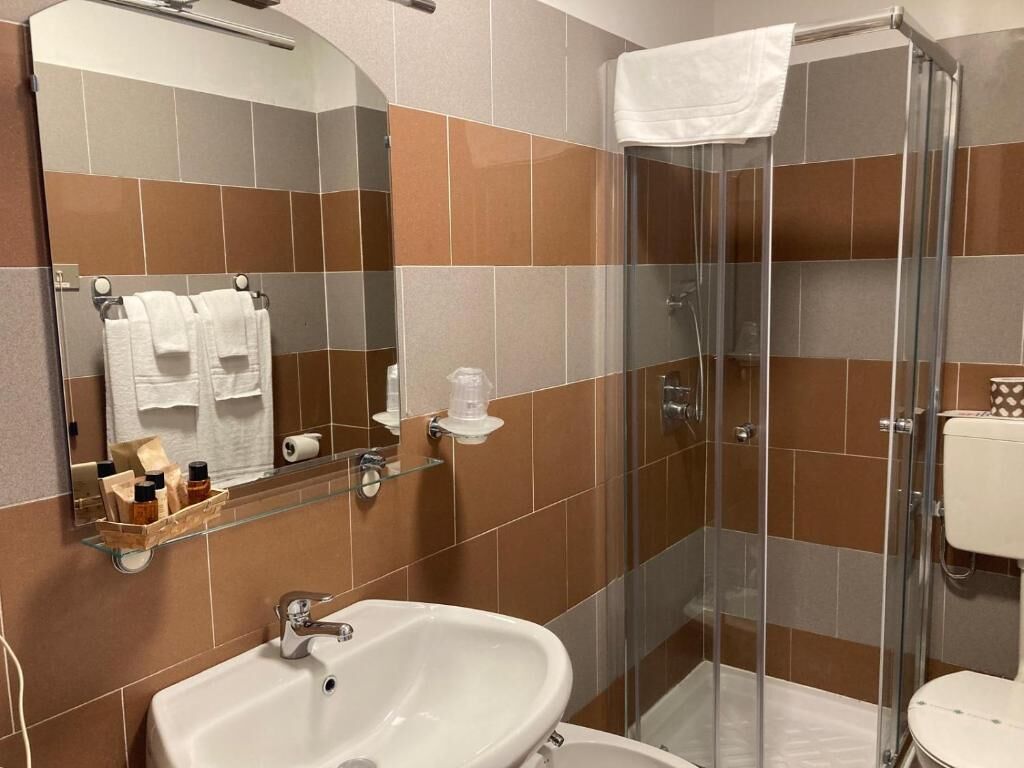A bathroom with a glass shower enclosure, a sink, and a toilet.