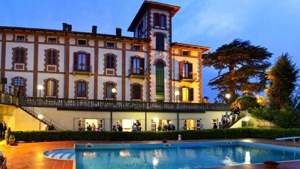 A historic building with a central tower, a swimming pool, and a covered walkway with people. - hotel Villa Conte Riccardi (Rocca D'Arazzo)