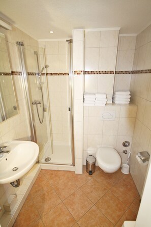 A bathroom with a glass-enclosed shower, a sink, a toilet, and a towel rack. - Cozy vacation apartment on the 1st floor in a quiet location in Wenningstedt (Wenningstedt)
