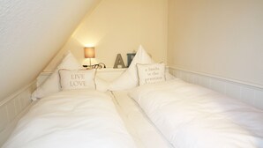 A bedroom with two single beds, each with a pillow that says "LIVE LOVE". There is a wall-mounted lamp and a decorative sign above the beds. - Cozy vacation apartment on the 1st floor in a quiet location in Wenningstedt (Wenningstedt)