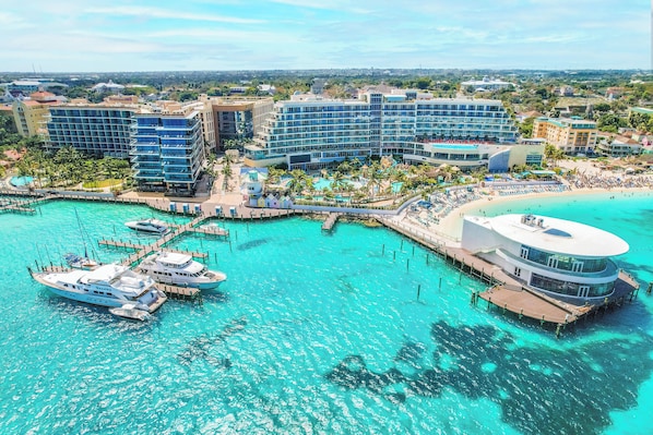 Ein Resort mit mehreren Gebäuden, einer Marina mit Booten und einem Strandabschnitt.