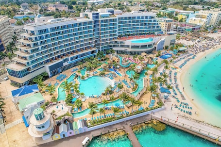 A resort with multiple swimming pools, a beach, and a large hotel building.