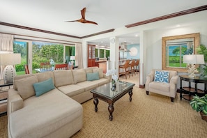 A spacious living room with a large sofa, a coffee table, and a dining area with chairs. - Waipouli Beach Resort G101 Oceanfront 2 BD 3 BA (Kapaa)