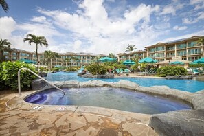 Ein Hotelpoolbereich mit mehreren Pools, Liegestühlen und Sonnenschirmen.