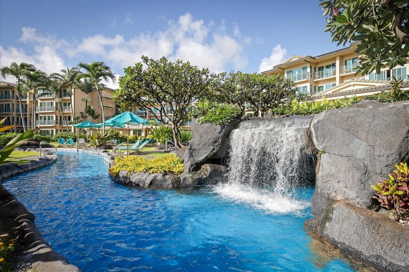 A hotel with a pool, a waterfall feature, and a building with balconies.