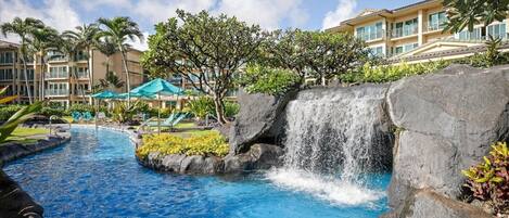 A hotel with a pool, a waterfall feature, and a building with balconies.