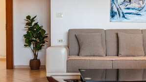 Ein modernes Wohnzimmer mit einer Couch, einem Couchtisch und einer Topfpflanze.