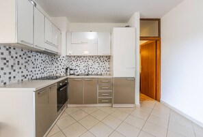Een moderne keuken met witte kasten, een betegelde spatwand en een houten deur die naar een andere kamer leidt.