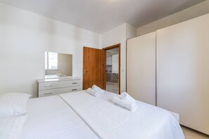 Een slaapkamer met een bed, een dressoir, een spiegel en een garderobe.