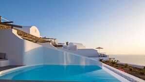Ett modernt semesterhotell med pool, vit arkitektur och utsikt över havet.
