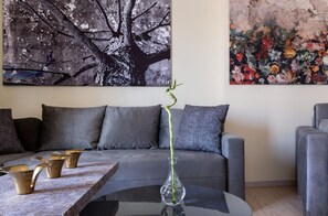 A modern living room with a grey sofa, a glass coffee table, and a vase with a green plant. - Apartment Fluvia, Divine Acropolis Views, Private Furnished Balcony, Athens (Athens)