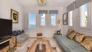 Ein Wohnzimmer mit einer Couch, einem Couchtisch, einem Fernseher und einem großen Fenster mit Blick.