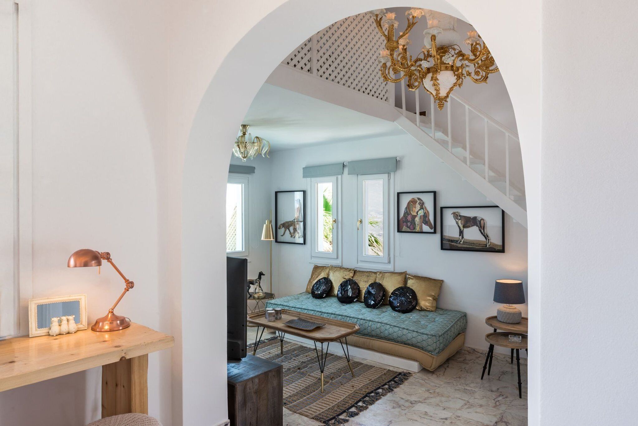 Ein gemütliches Wohnzimmer mit einem Holztisch, einer Couch mit dekorativen Kissen und einer Treppe, die in eine obere Etage führt.