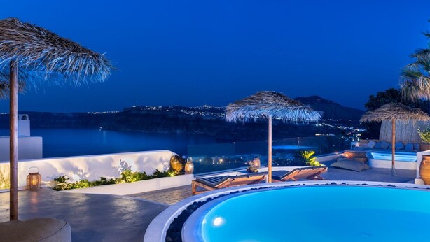 Ein Poolbereich mit Liegestühlen, Sonnenschirmen und Blick auf das Meer in der Nacht.