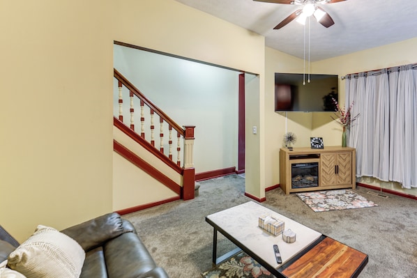 A living room with a brown leather couch, a coffee table, a wooden cabinet, and a staircase.