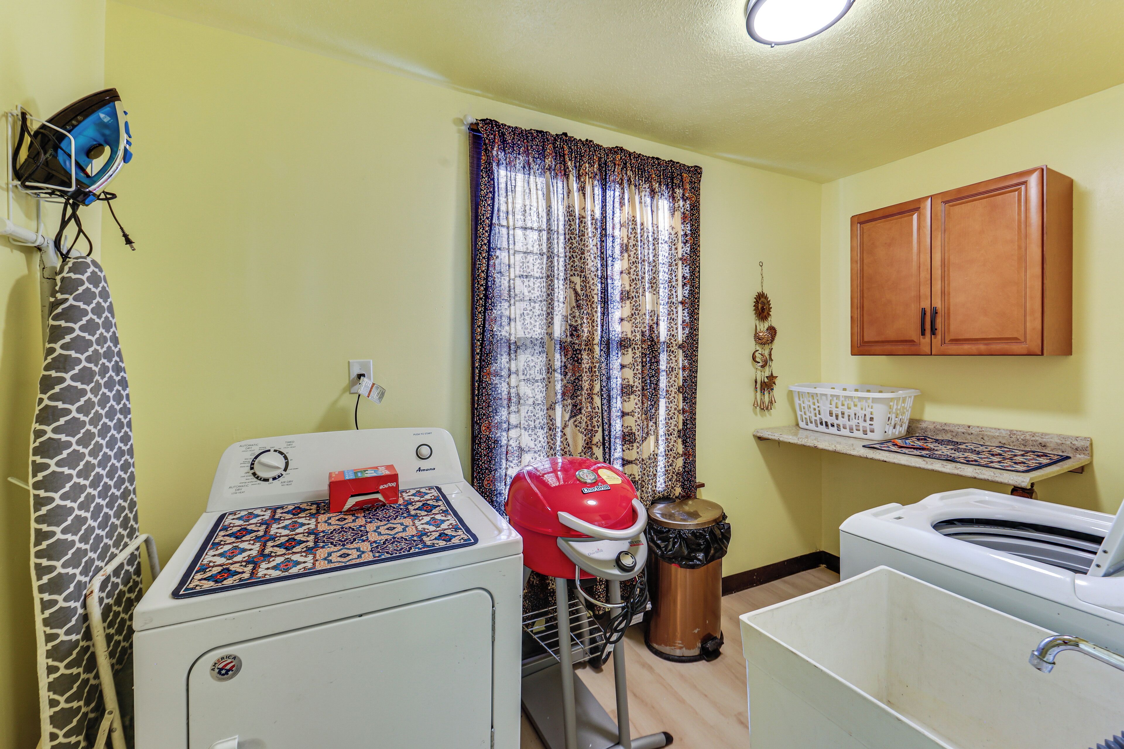 A laundry area with a washing machine, dryer, and ironing board.