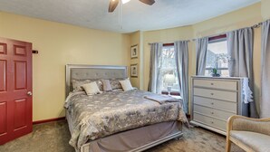 Un dormitorio con cama, cómoda, silla y ventilador de techo.