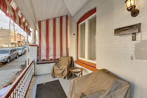A covered porch with a striped awning, a mailbox, and covered furniture.