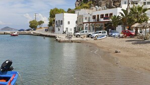 A coastal area with a sandy beach, parked cars, and a small boat.