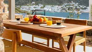 Una mesa de madera con productos para el desayuno y vistas a un pueblo costero.