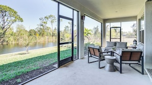 A spacious balcony with a view of a lake and trees, furnished with a sofa and chairs. - 1 Mi to Boat Launch: Canal-view Cape Coral Gem (Cape Coral)