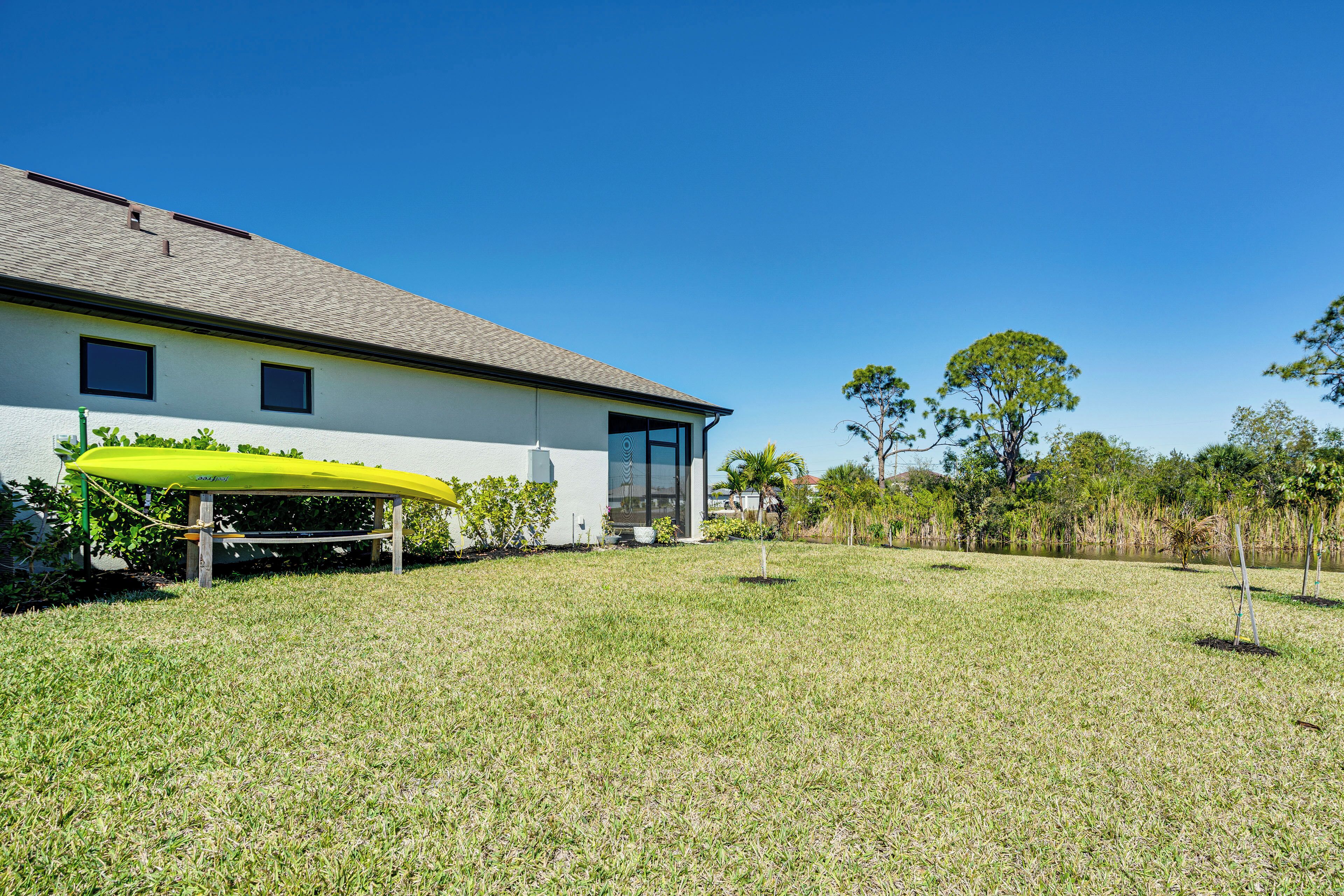 A modern house with a flat roof, a covered patio, and a well-maintained lawn.