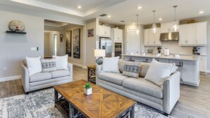 A modern living room with two sofas, a coffee table, and a kitchen area with white cabinets and stainless steel appliances. - 1 Mi to Boat Launch: Canal-view Cape Coral Gem (Cape Coral)