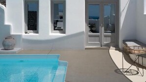 A modern white villa with a swimming pool, a covered patio, and a view of the sea. - Endearing Santorini Suite | Aegean Serenity Suite | Junior Suite with Private. (Santorini)