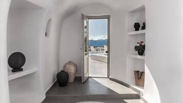 Un couloir donnant sur les montagnes grâce à une porte ouverte, et menant à un balcon.