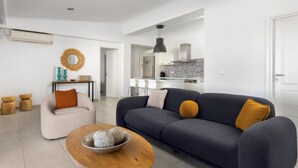 Una sala moderna con sofá, mesa de centro y comedor con sillas.