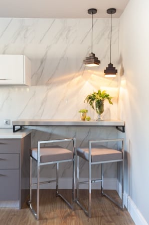 Une cuisine moderne avec un dosseret en marbre, des luminaires suspendus et des tabourets de bar.